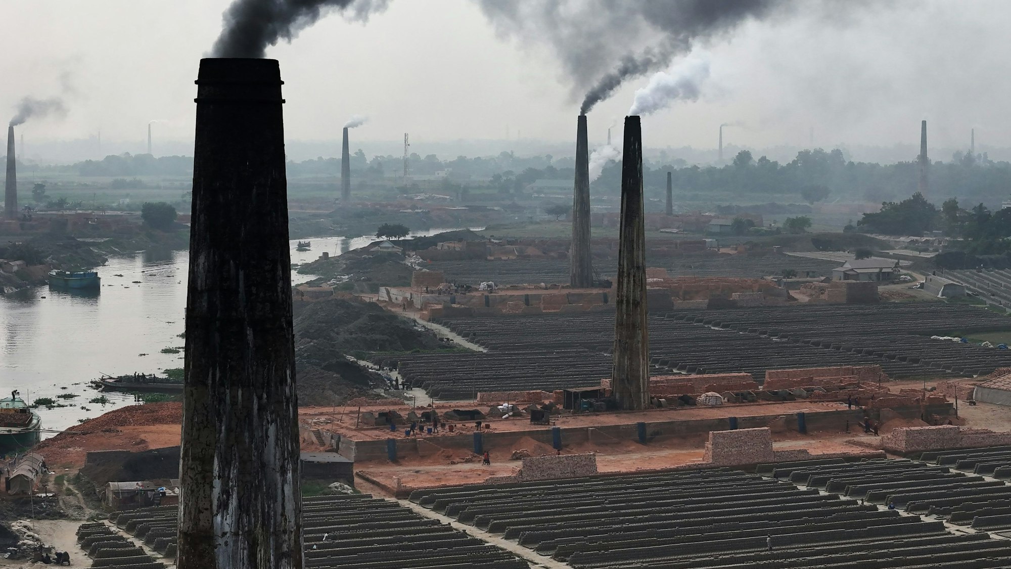 Rauch steigt aus den Schornsteinen einer Ziegelsteinfabrik auf.