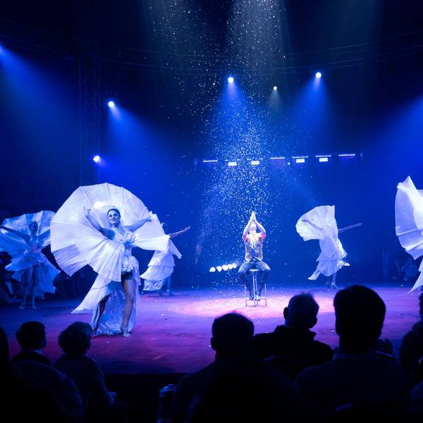 30.11.2024, Premiere des 9. Kölner WeihnachtsCircus in Köln. Eine blaubeleuchtete Manege mit fünf TänzerInnen und Konfettiregen.