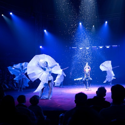 30.11.2024, Premiere des 9. Kölner WeihnachtsCircus in Köln. Eine blaubeleuchtete Manege mit fünf TänzerInnen und Konfettiregen.