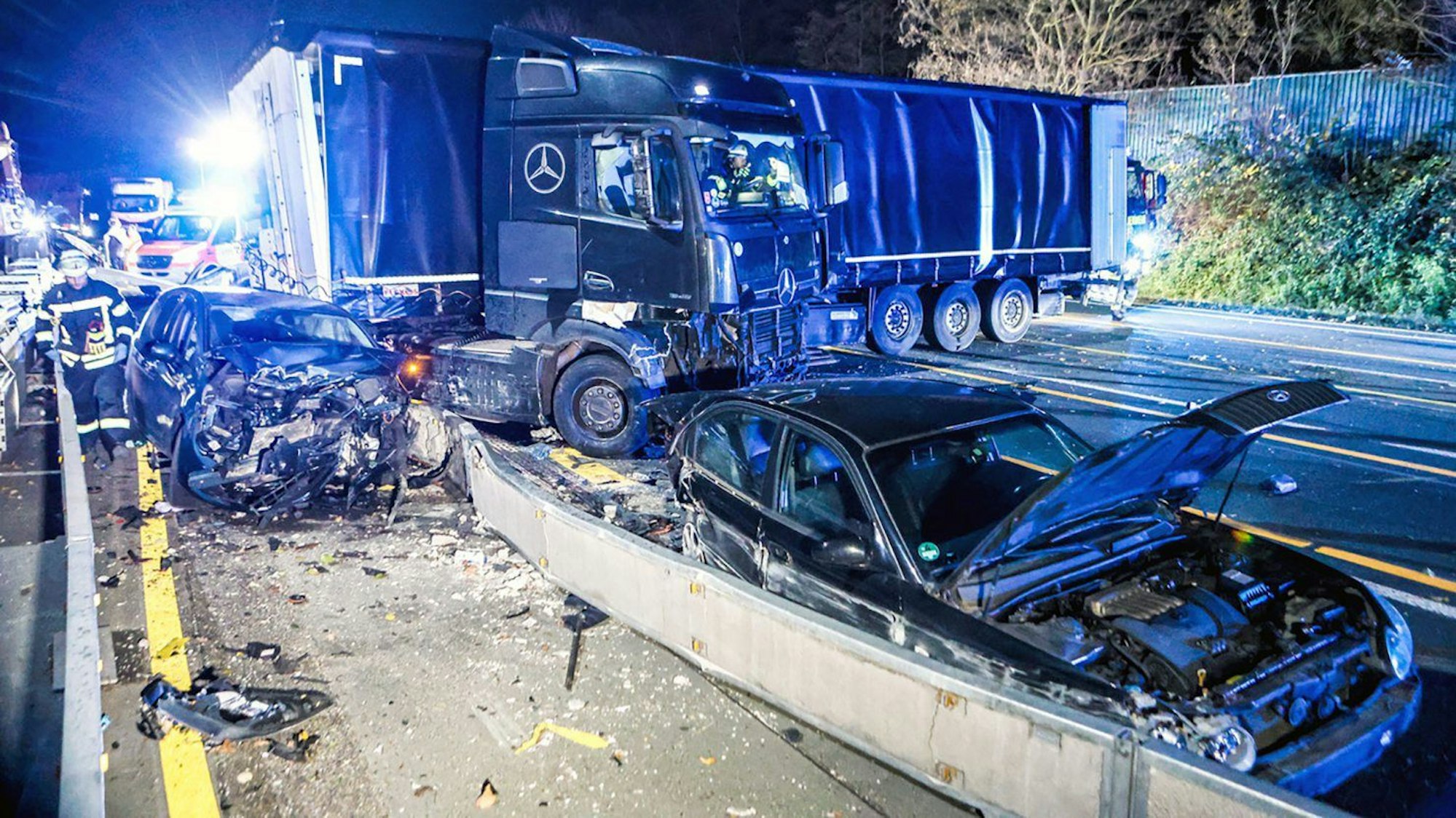Ein Lastwagen steht quer auf der Autobahn 1 bei Hagen an der Unfallstelle neben beschädigten Autos.