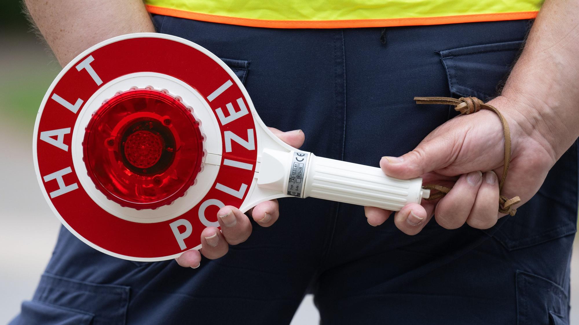Ein Polizist mit Kelle steht an einer Tempo 30 Zone.