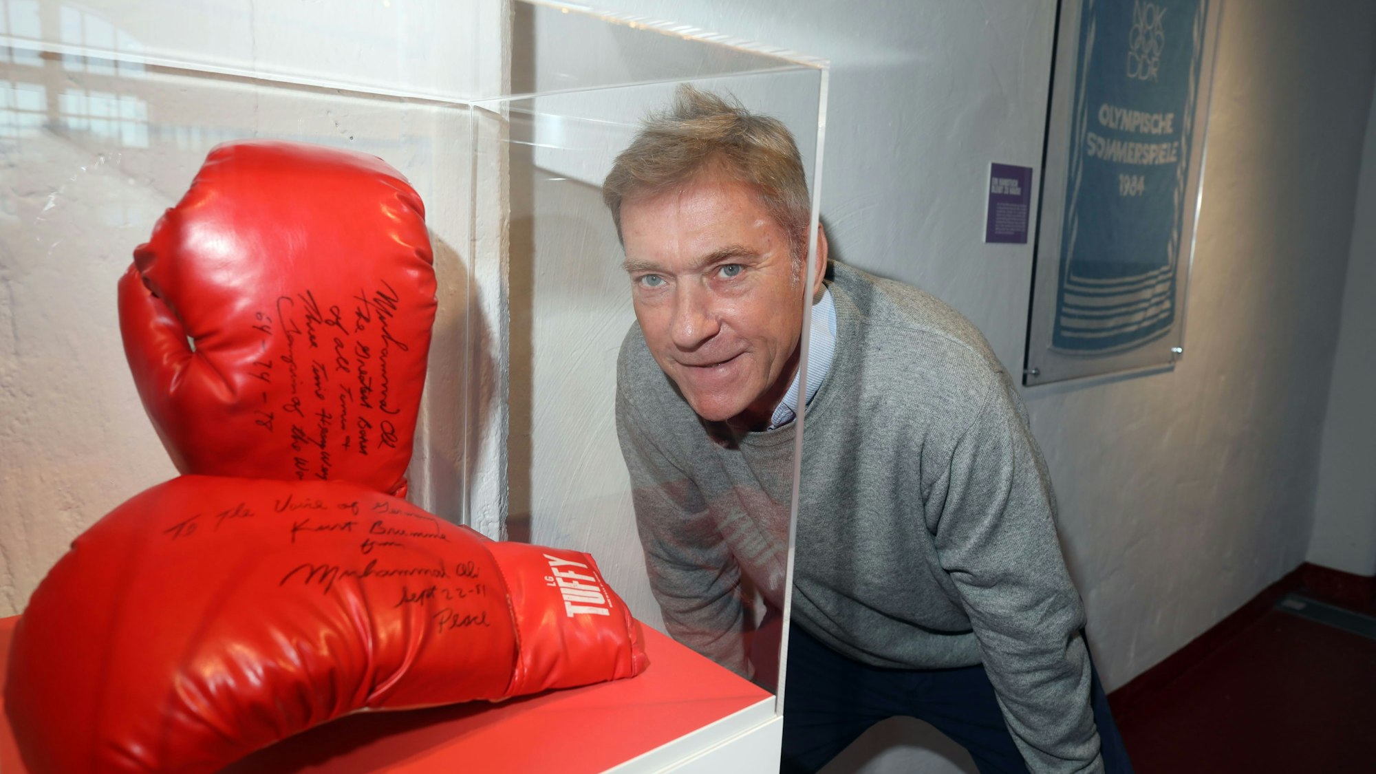 Andreas Höfer zwischen den Boxhandschuhen von Muhammad Ali und einem Handtuch von den Olympischen Sommerspielen 1984. Zum 25. Geburtstag präsentiert das Deutsche Sport & Olympia Museum 25 herausragende Objekte in einer Sonderaustellung.