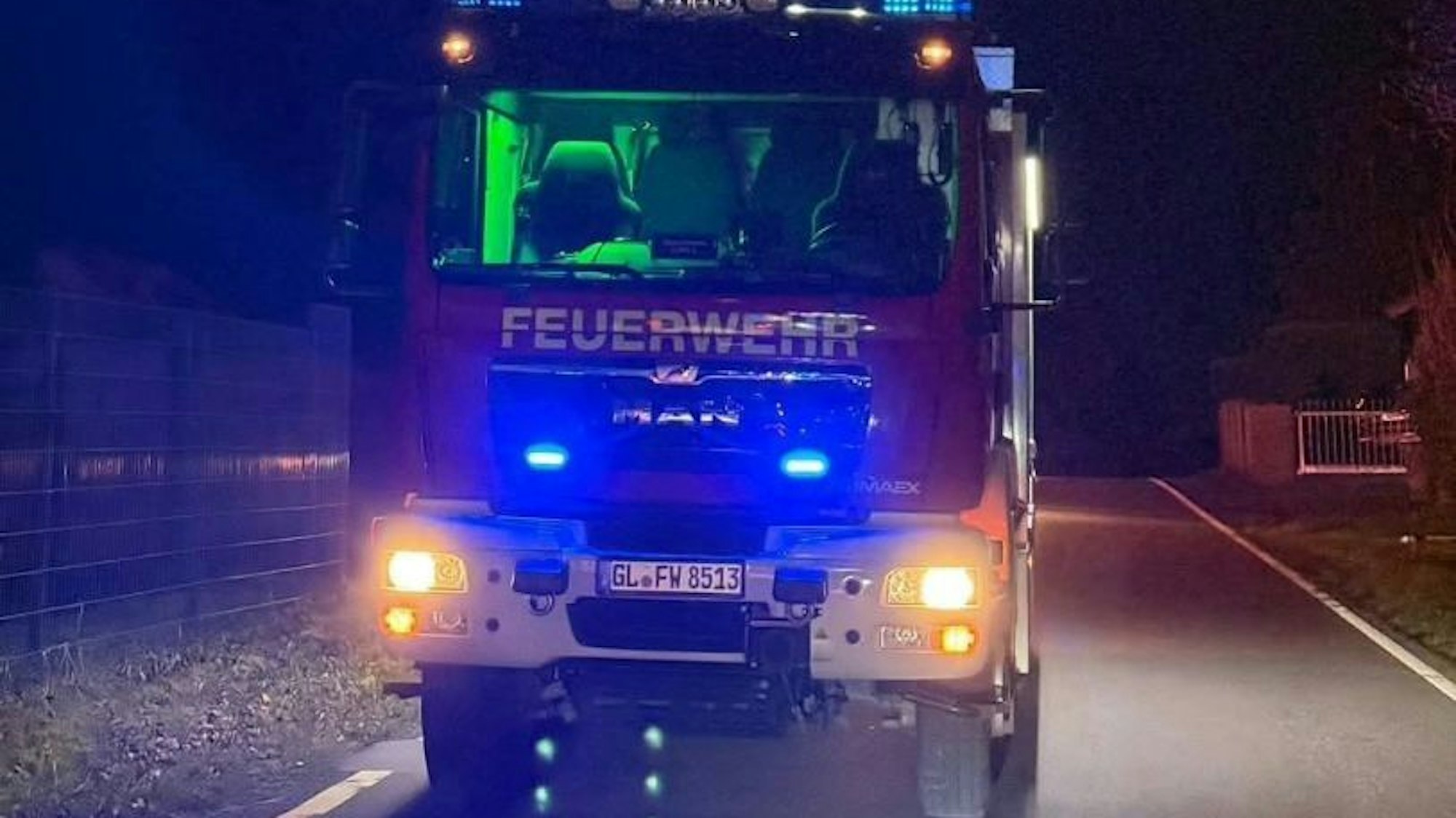 Ein Feuerwehrfahrzeug mit ausgefahrenem Lichtmast steht auf der dunklen landstra0e 84 bei Overath-Hufe.