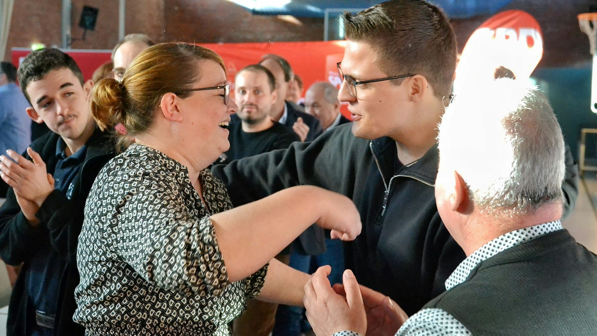 Andrea Kanonenberg steht inmitten ihrer applaudierenden Parteigenossen.