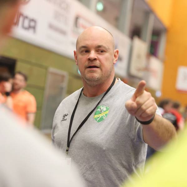 Szene einer Auszeit beim Handball, in der der Trainer etwas erklärt.