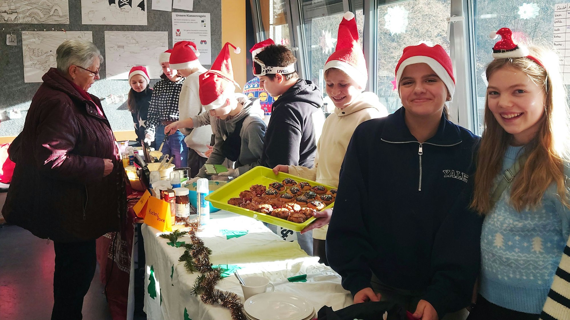 Schüler mit Nikolausmütze stehen bei einem Basar an einem Stand.