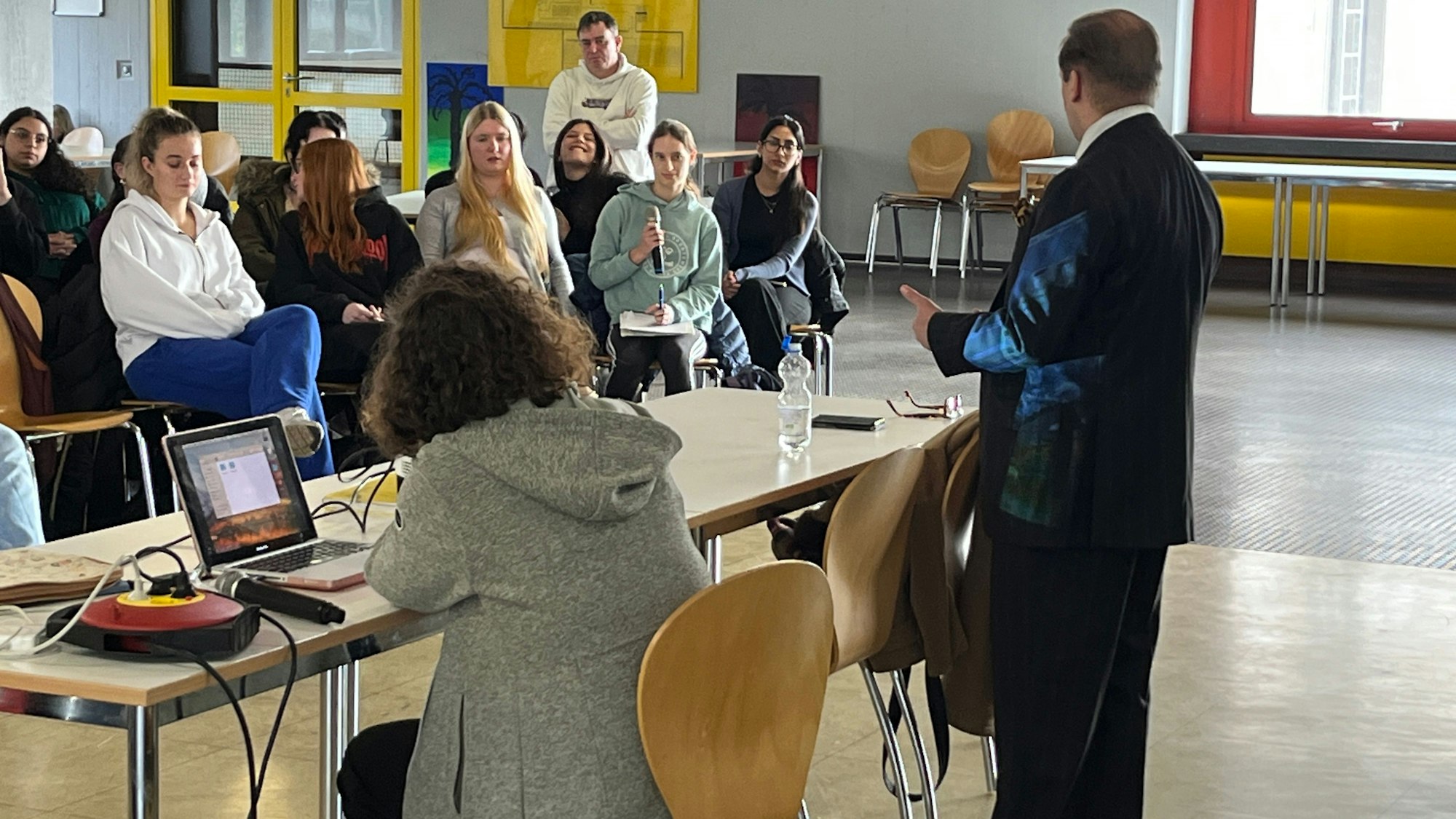 Eine Schülerin hat ein Mikrofon in der Hand und stellt eine Frage.