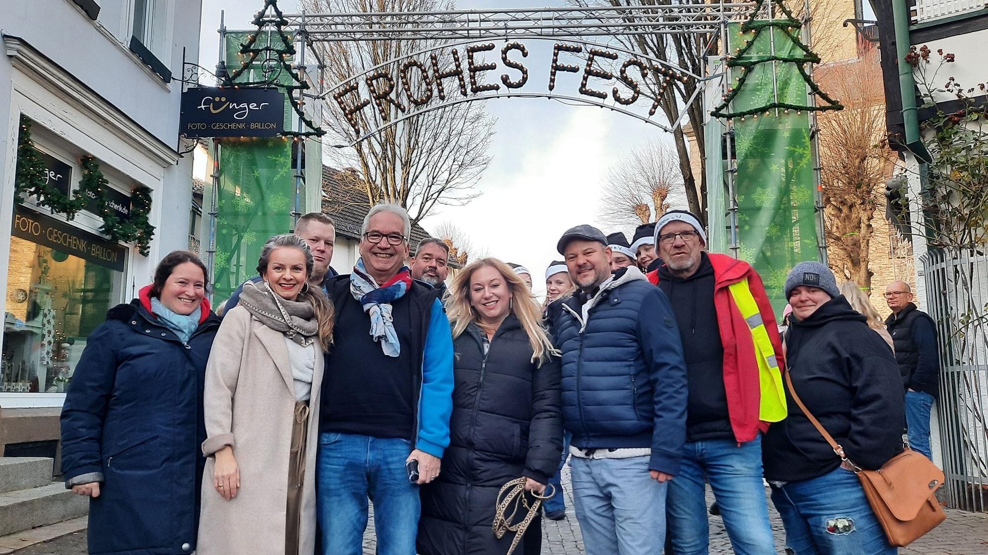 Eine Gruppe unter dem Leuchtschriftzug „Frohes Fest“.
