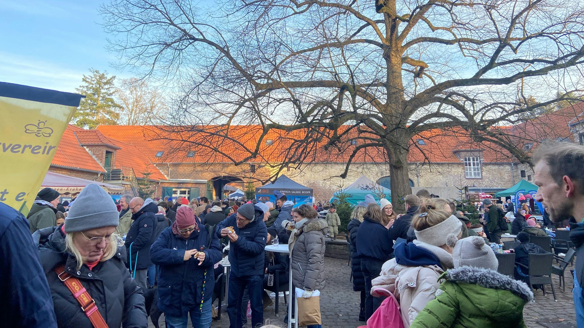 Viele Menschen stehen in einem großen Hof einer Hofanlage.