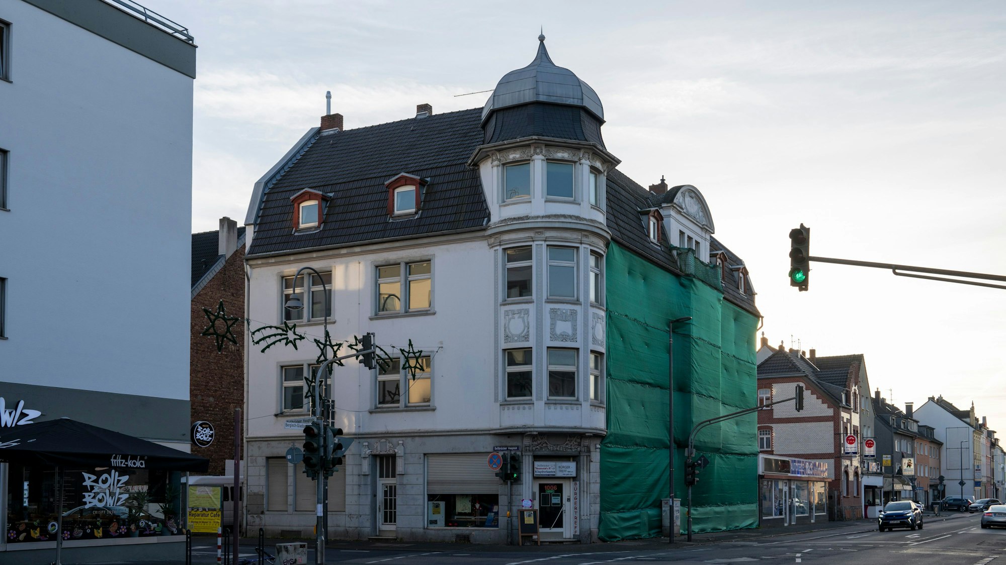 Blick auf ein Eckhaus mit markanter Fassade, die zum Teil verhüllt ist.