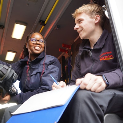 Das Foto zeigt eine junge Frau und einen jungen Mann in einem Feuerwehr-Fahrzeug.