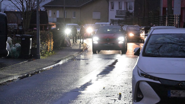 Auf der schmalen Straße parken Autos und verengen die Fahrbahn.