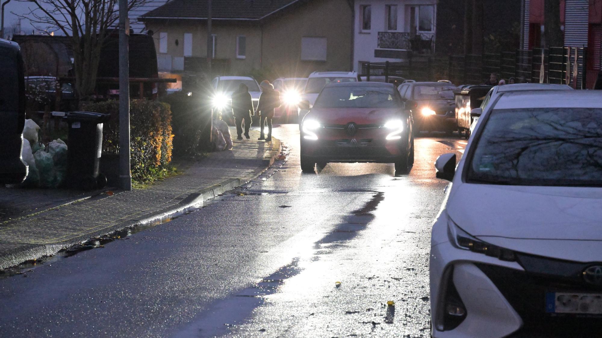 Auf der schmalen Straße parken Autos und verengen die Fahrbahn.