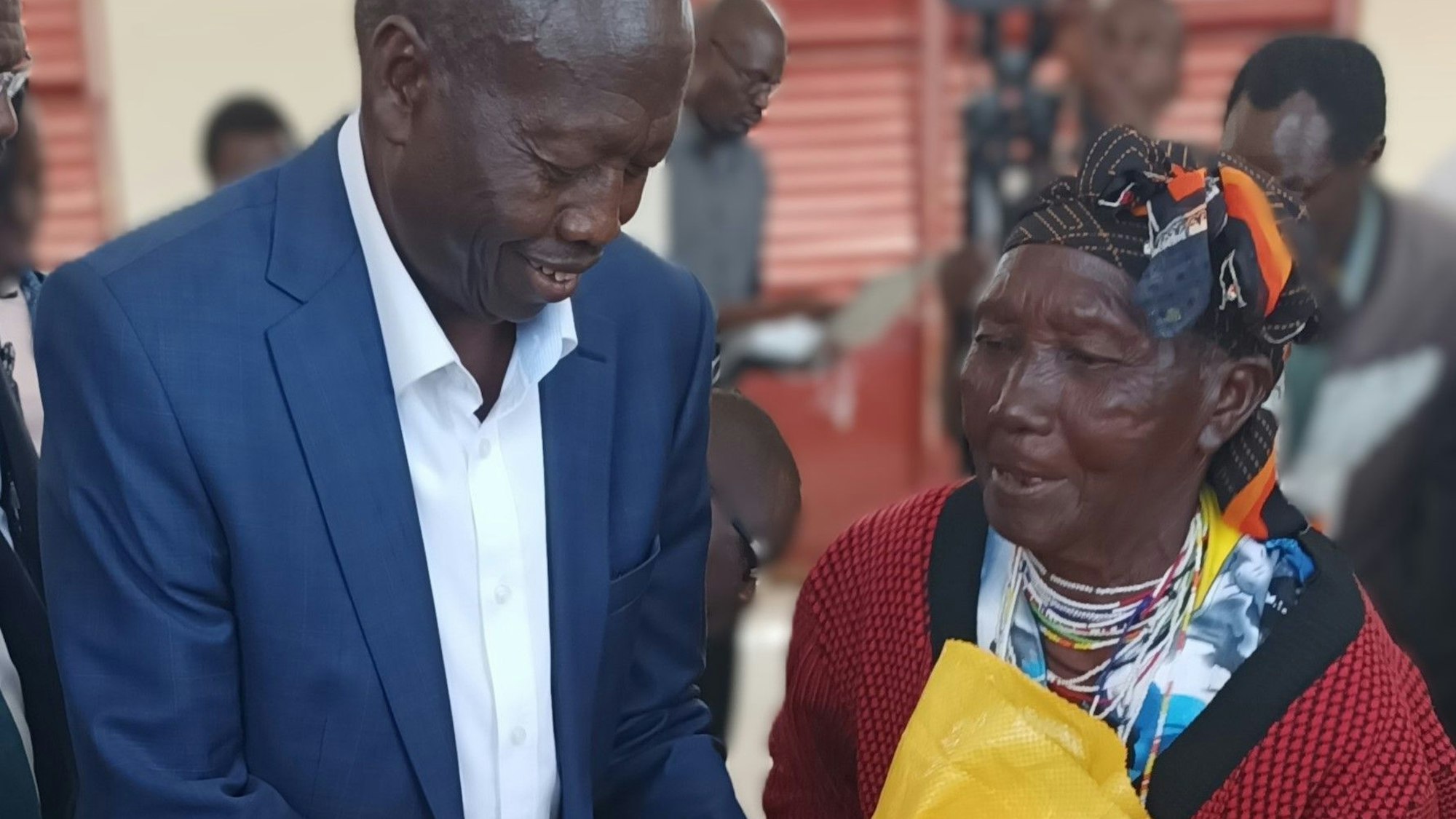 Das Foto zeigt einen Mann, der einer Frau einen Plastiksack mit Lebensmitteln übergibt.