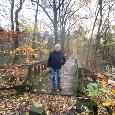 Ein Mann steht auf einer Holzbrücke in einem Wald
