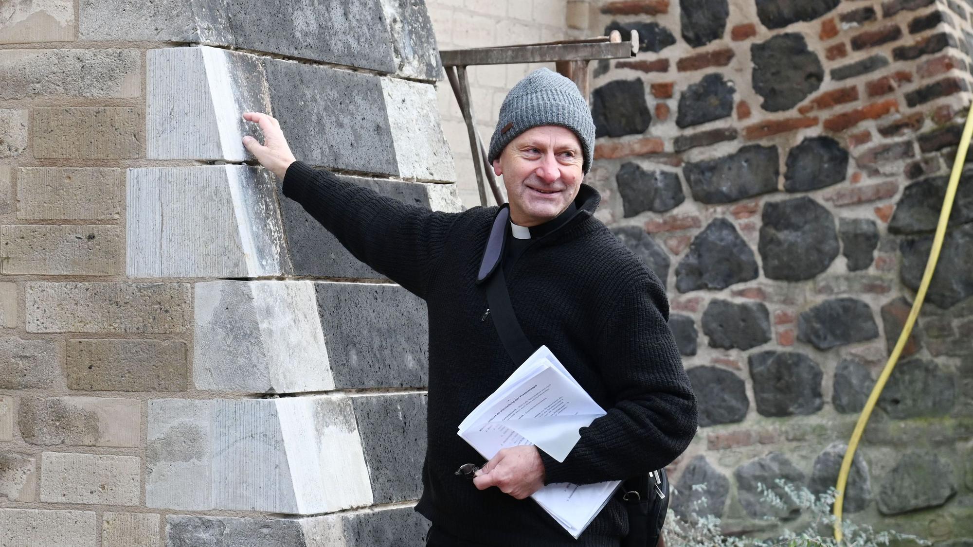 Zu sehen ist Pfarrer Hildebrandt an der Kirchenmauer von St. Pantaleon.