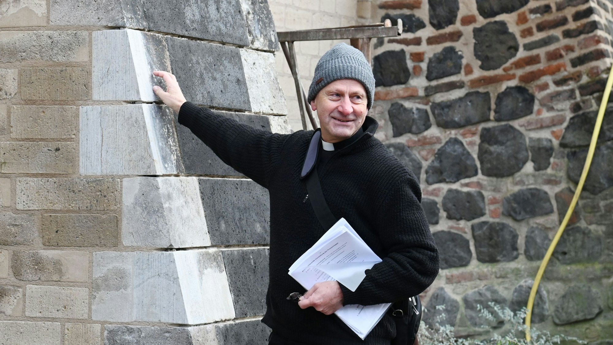 Zu sehen ist Pfarrer Hildebrandt an der Kirchenmauer von St. Pantaleon.