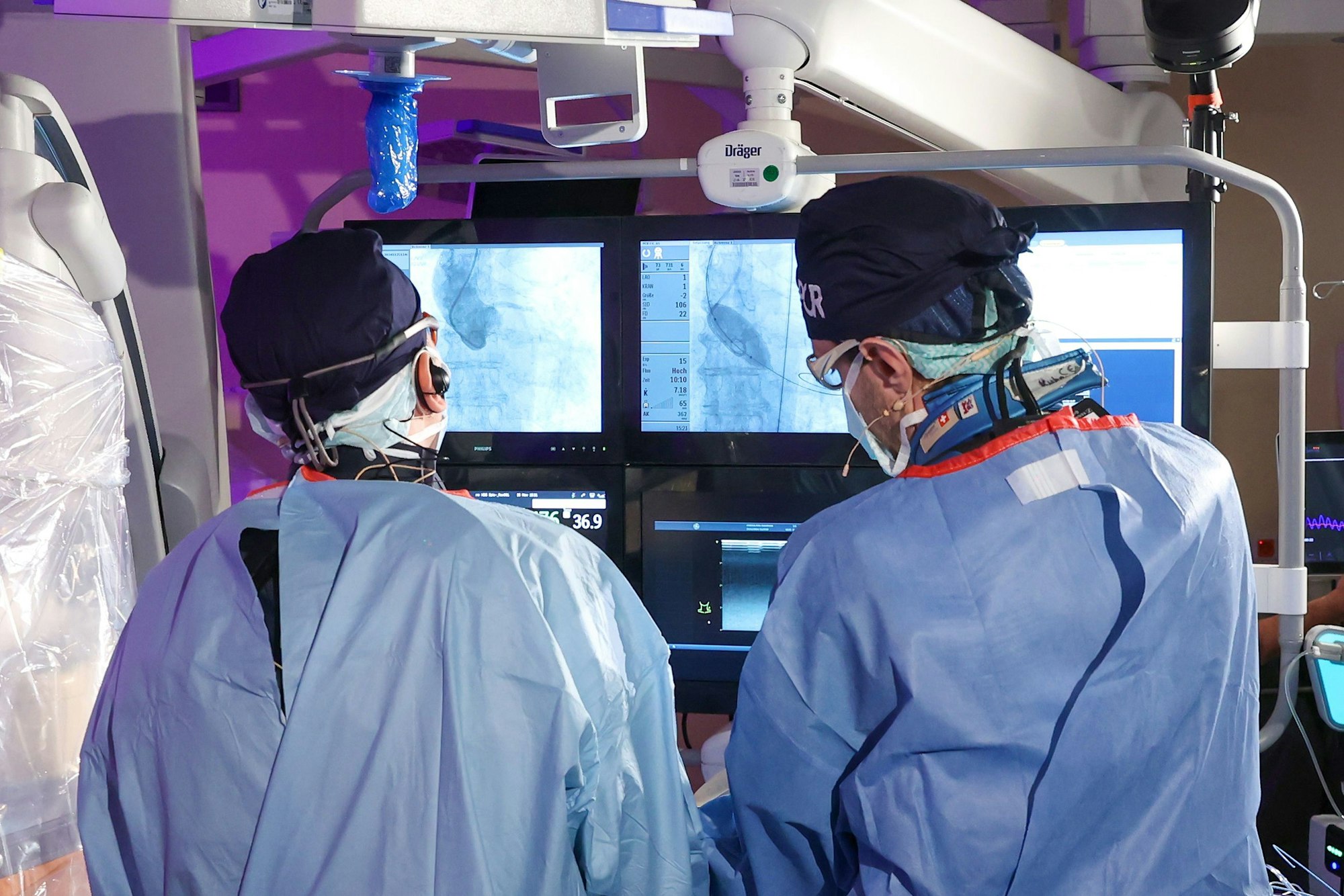 Zwei Ärzte operieren am Herzen und gucken auf den Bildschirm