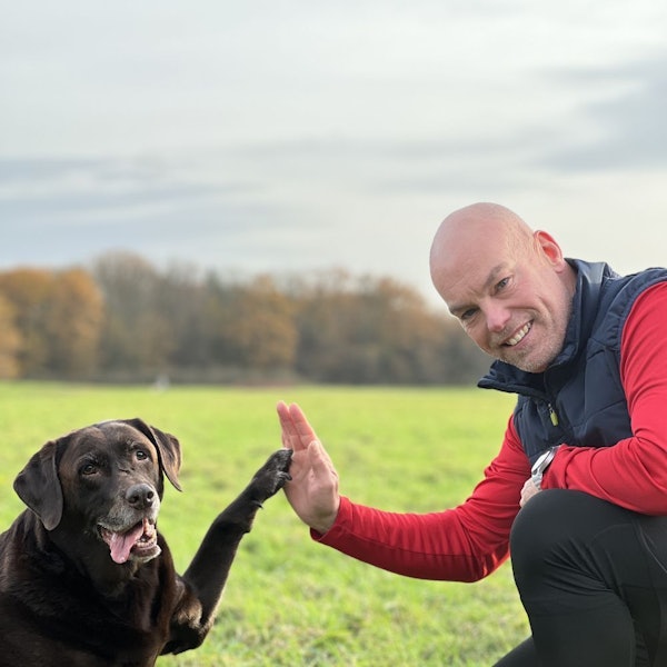 Manni Hartmann und sein Hund grüßen sich mit Hand und Pfote.