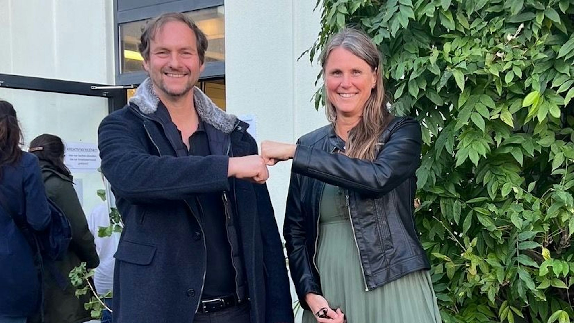 Ein Mann und eine Frau lachen in die Kamera und geben sich einen Faust-Gruß.