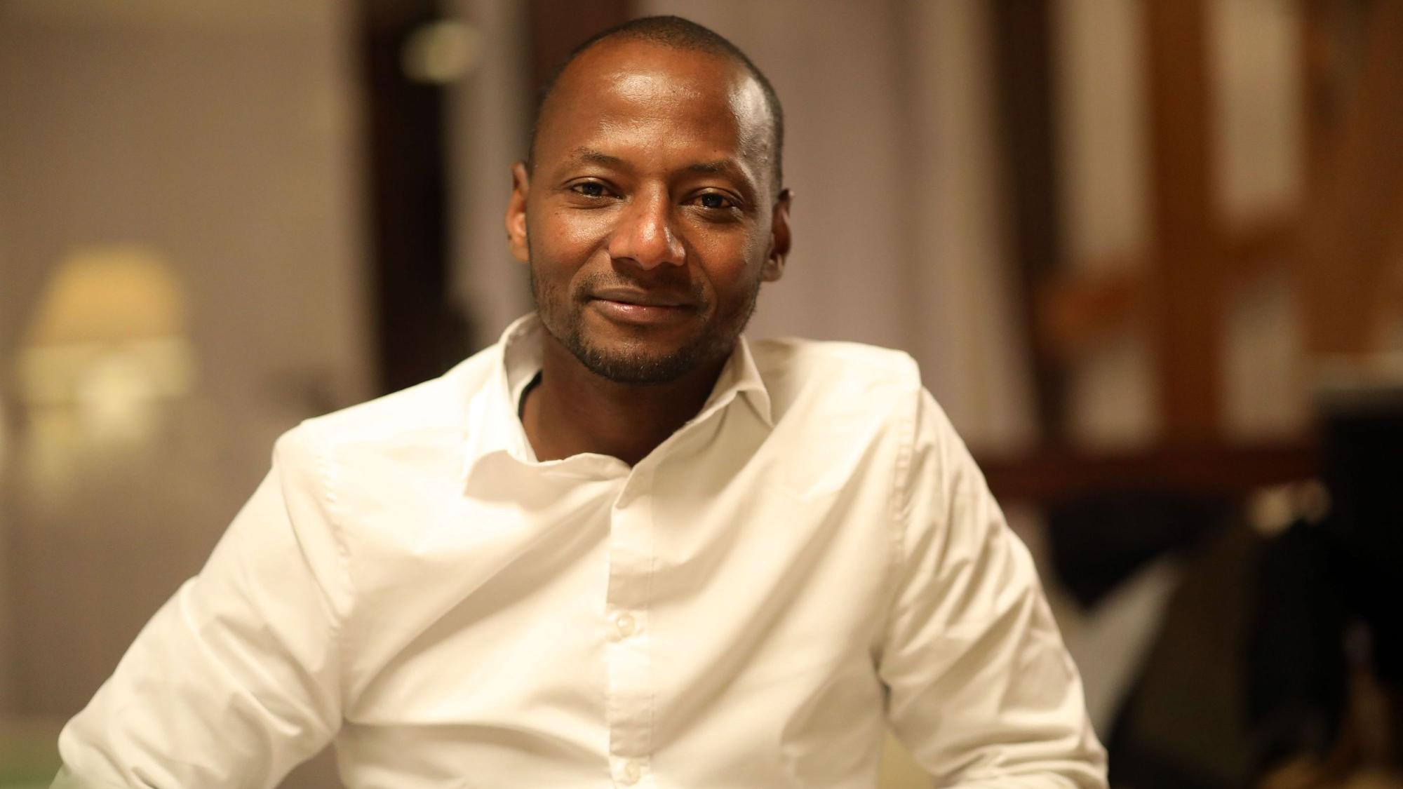 Wie Alhassane Barry aus Guinea einen Job fand und so in Deutschland ankam: Ein Porträt von Barry im weißen Hemd.