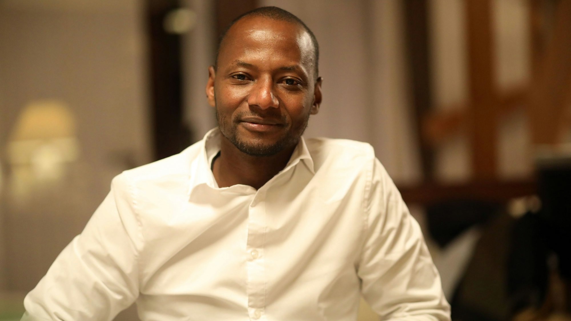 Wie Alhassane Barry aus Guinea einen Job fand und so in Deutschland ankam: Ein Porträt von Barry im weißen Hemd.