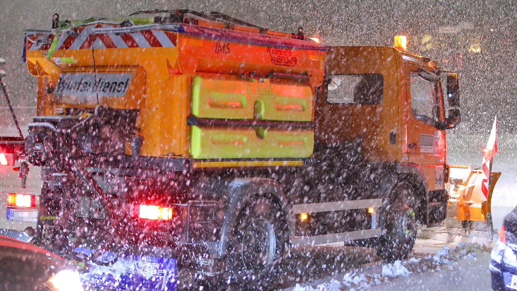 Ein Schneepflug räumt eine glatte schneebedeckte Straße.