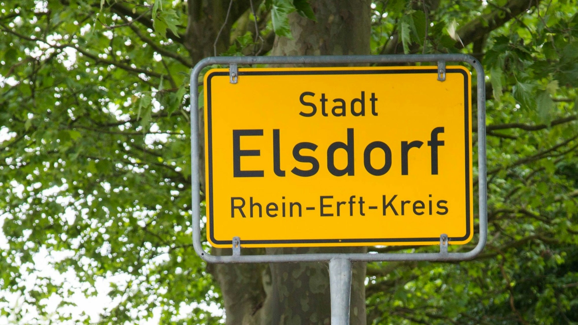 Auf dem Foto ist ein gelbes Ortsschild zu sehen.