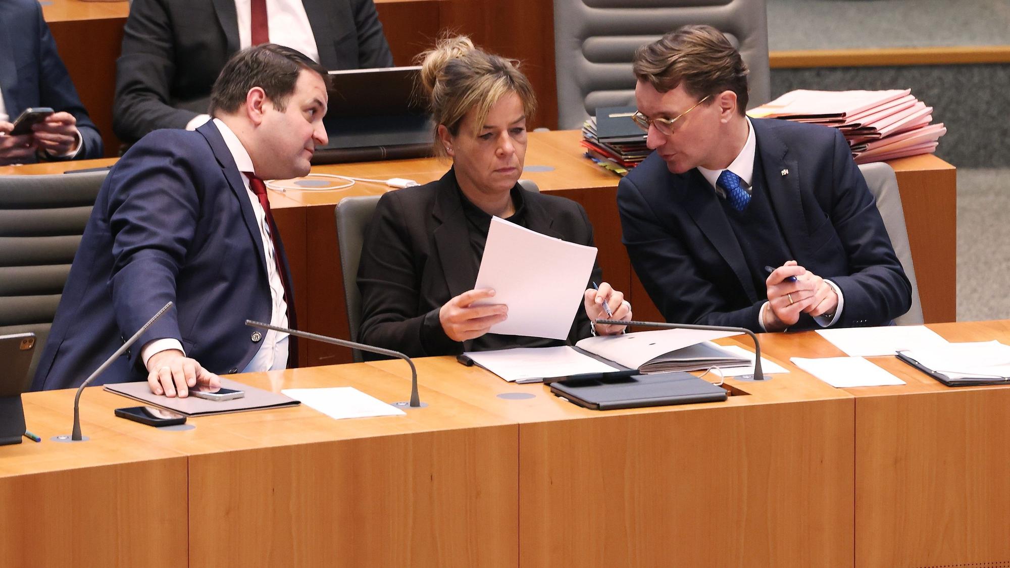 Nathanael Liminski (CDU, l-r), Minister für Bundes- und Europaangelegenheiten, im Gespräch mit der nordrhein-westfälischen Vize-Ministerpräsidentin Mona Neubauer (Bündnis 90/Die Grünen) und Ministerpräsident Hendrik Wüst (CDU) während einer Plenarsitzung des Landtags.