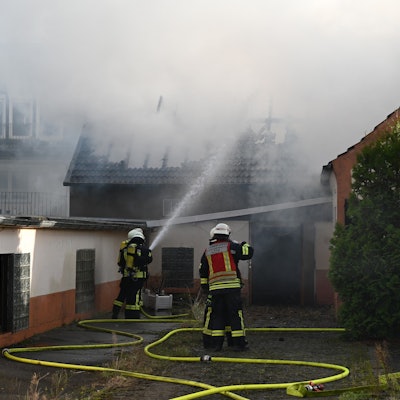 Das Foto zeigt Feuerwehrleute, die das Feuer löschen. Der Dachstuhl ist schon komplett abgebrannt.