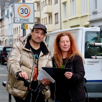 Tom Geffe und Caroline Michel sind mit dem Bebauungsplan auf dem Teil Gerolsteiner Straße unterwegs, wo 15 Bäume fehlen.