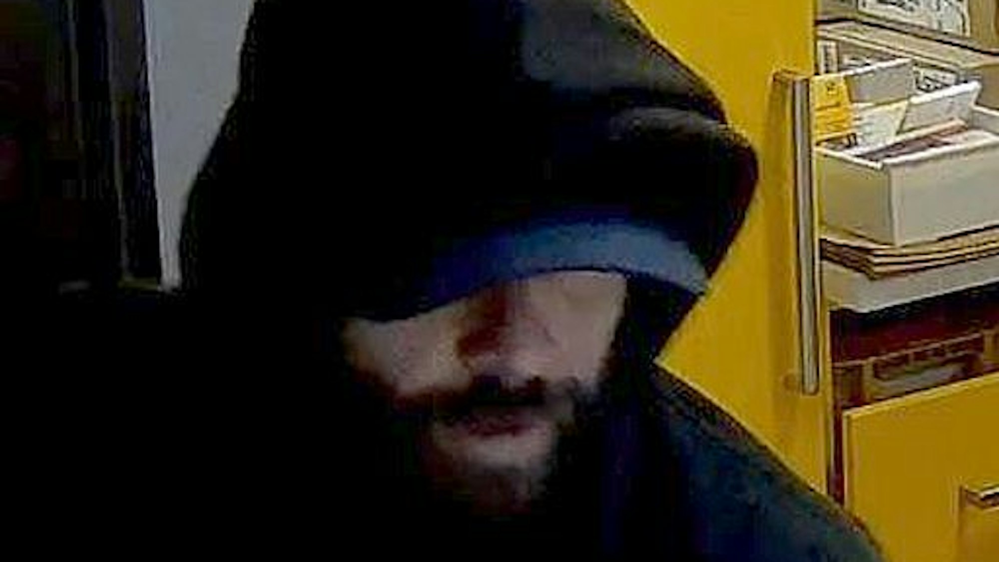 Bild aus einer Überwachungskamera von einem Mann mit schwarzer Kapuze in einem Kiosk