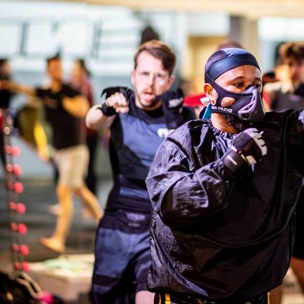 Das Bild zeigt den Kampfsportler Steavano Kojo Tuekpe, wie er durch das Trainingscenter läuft und dabei wie ein Boxer die Fäuste in die Luft schlägt.