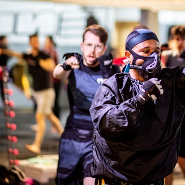 Das Bild zeigt den Kampfsportler Steavano Kojo Tuekpe, wie er durch das Trainingscenter läuft und dabei wie ein Boxer die Fäuste in die Luft schlägt.