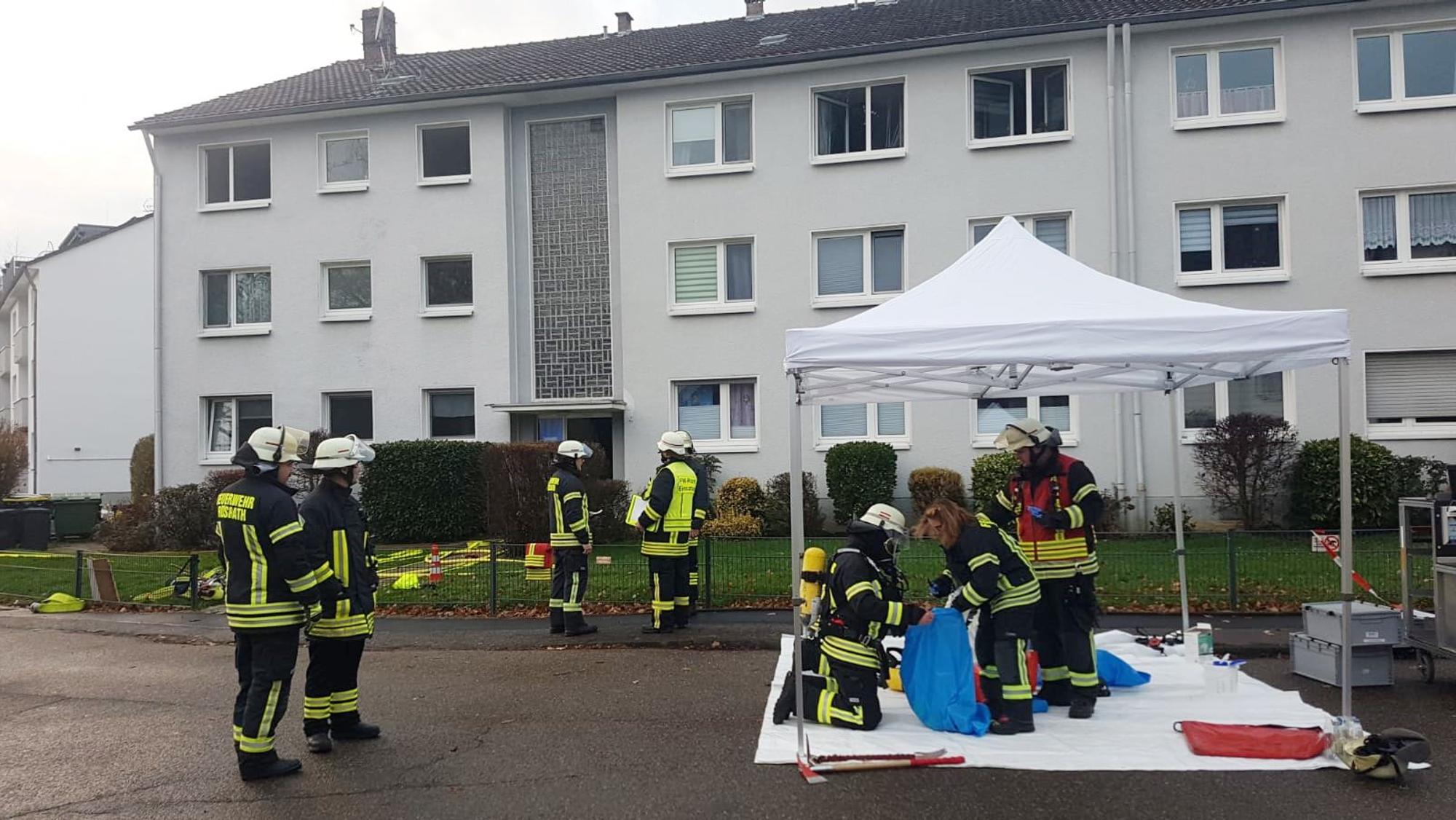 Feuerwehrleute stehen vor einem Mehrfamilienhaus in Rösrath.