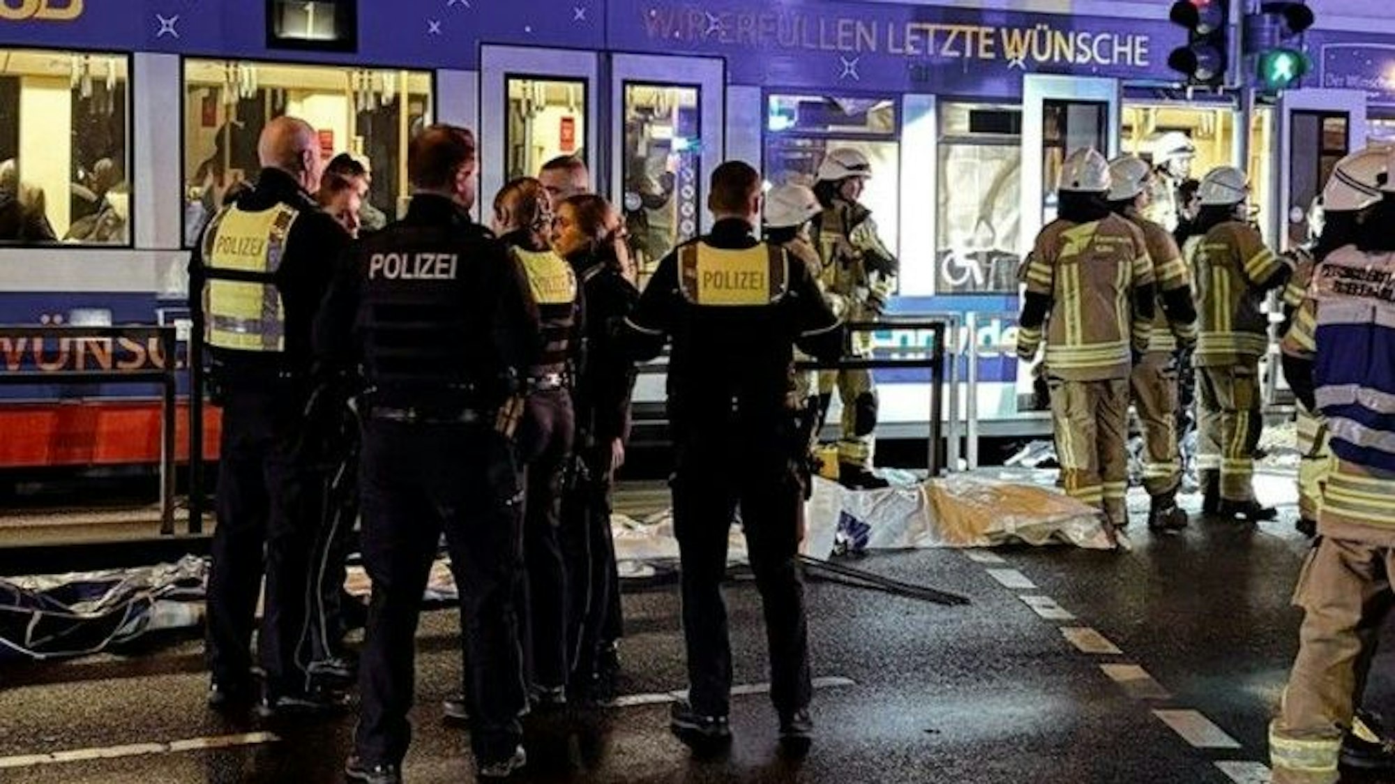 Mehrere Einsatzkräfte der Polizei und der Feuerwehr stehen an der Straßenbahn an der Aachener Straße.