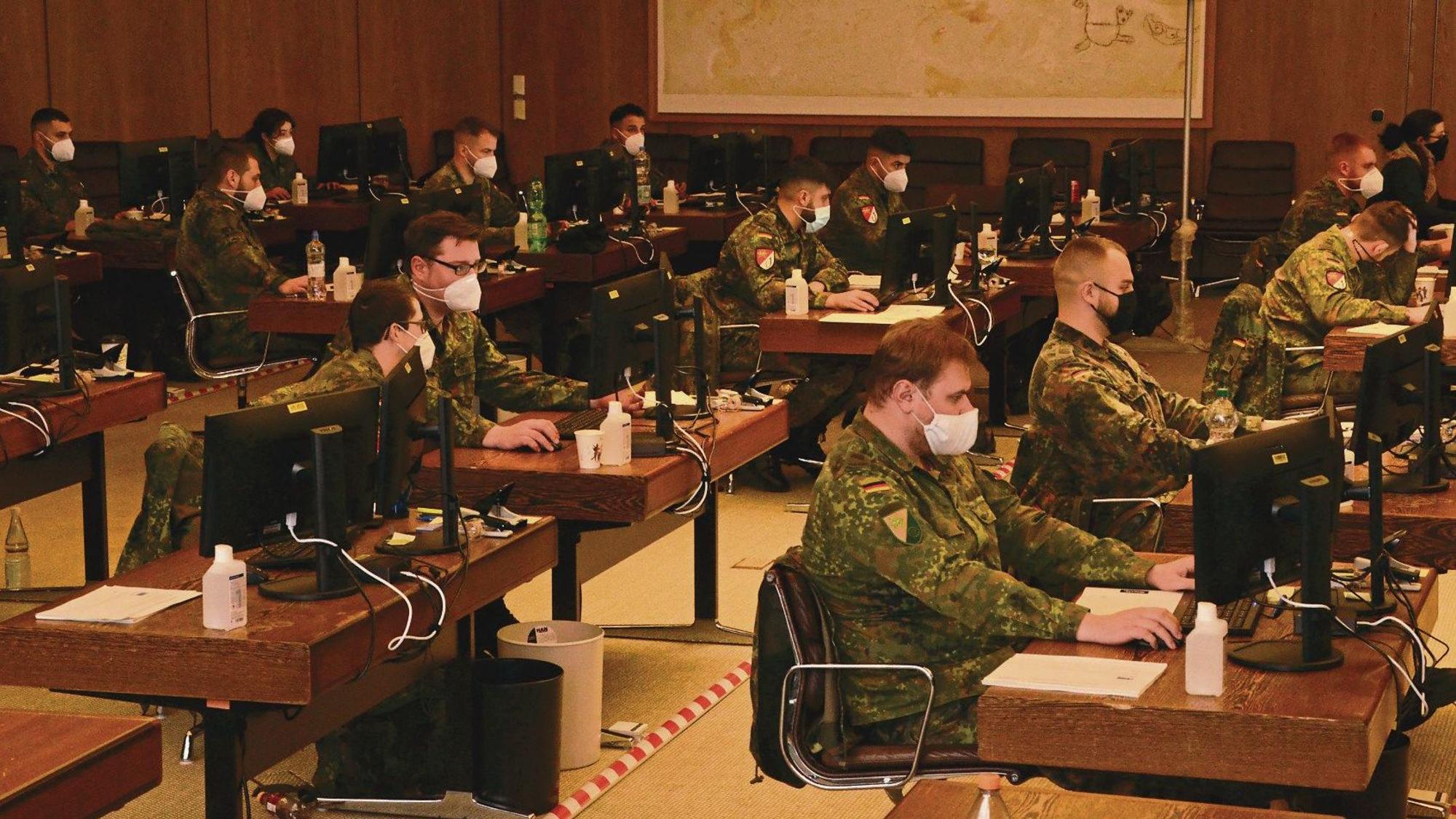 Soldatinnen und Soldaten der Bundeswehr in einem Sitzungssaal. Alle tragen FFP2-Masken