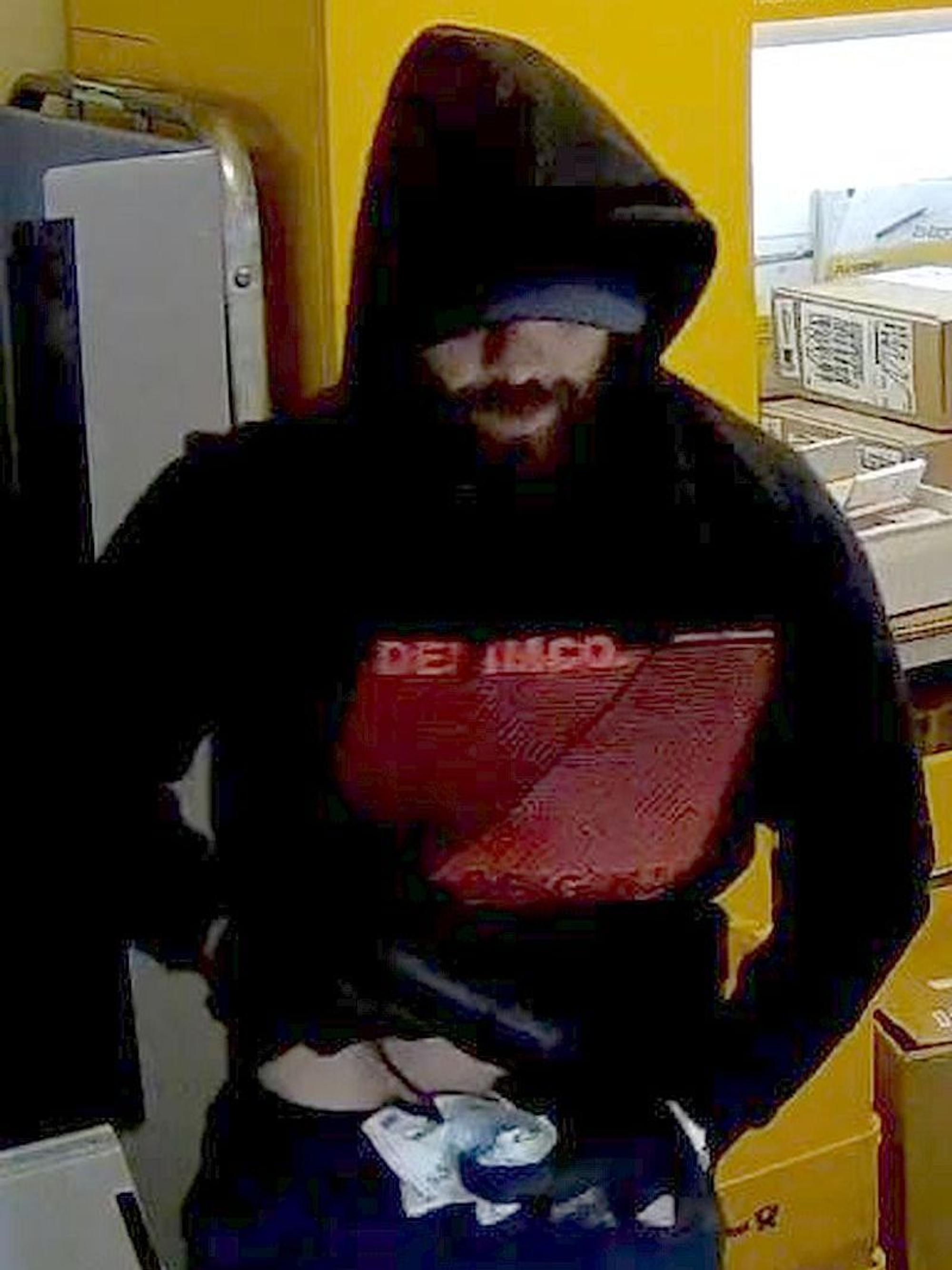 Bild aus einer Überwachungskamera von einem Mann mit schwarzer Kapuze in einem Kiosk