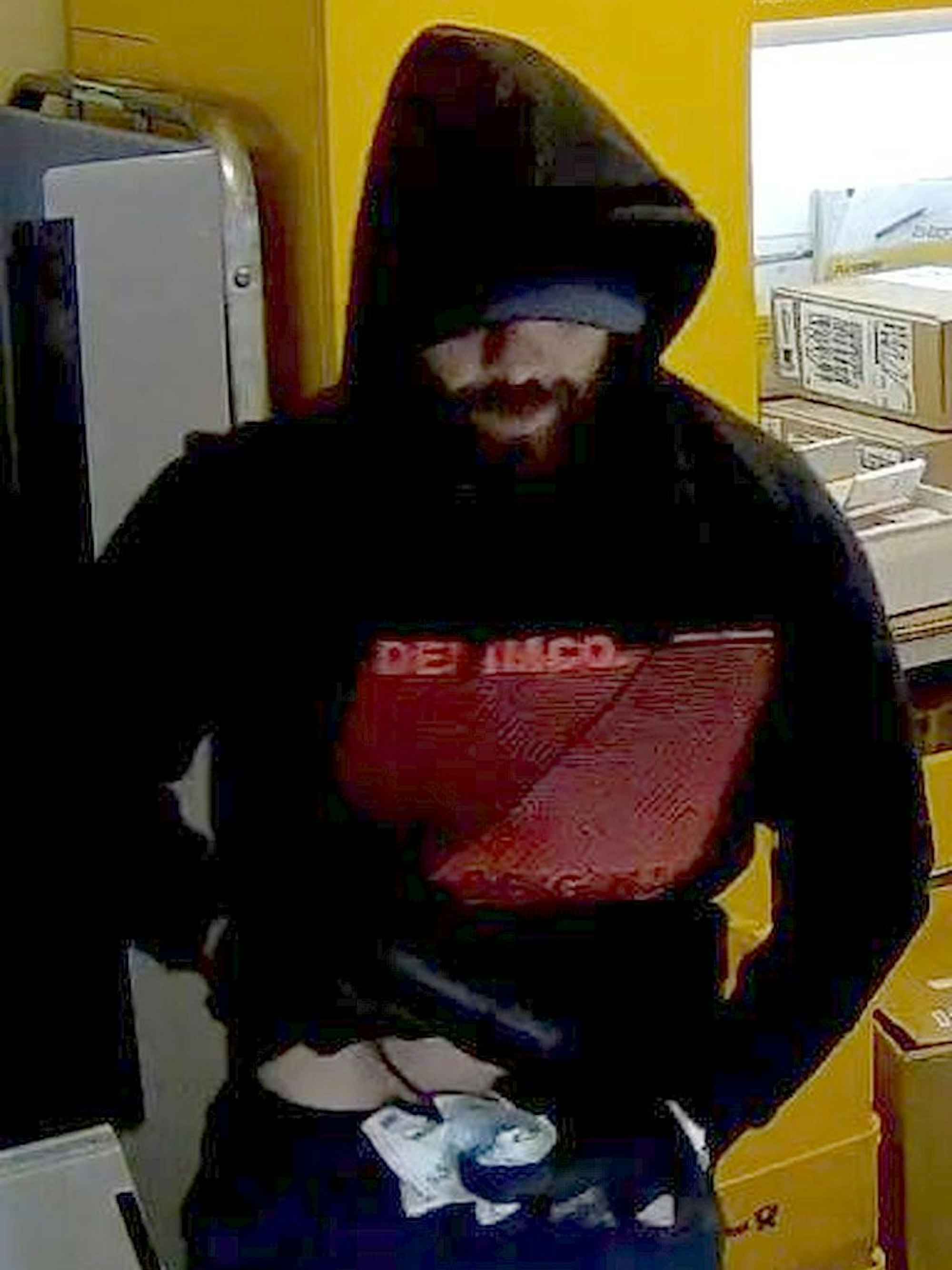 Bild aus einer Überwachungskamera von einem Mann mit schwarzer Kapuze in einem Kiosk