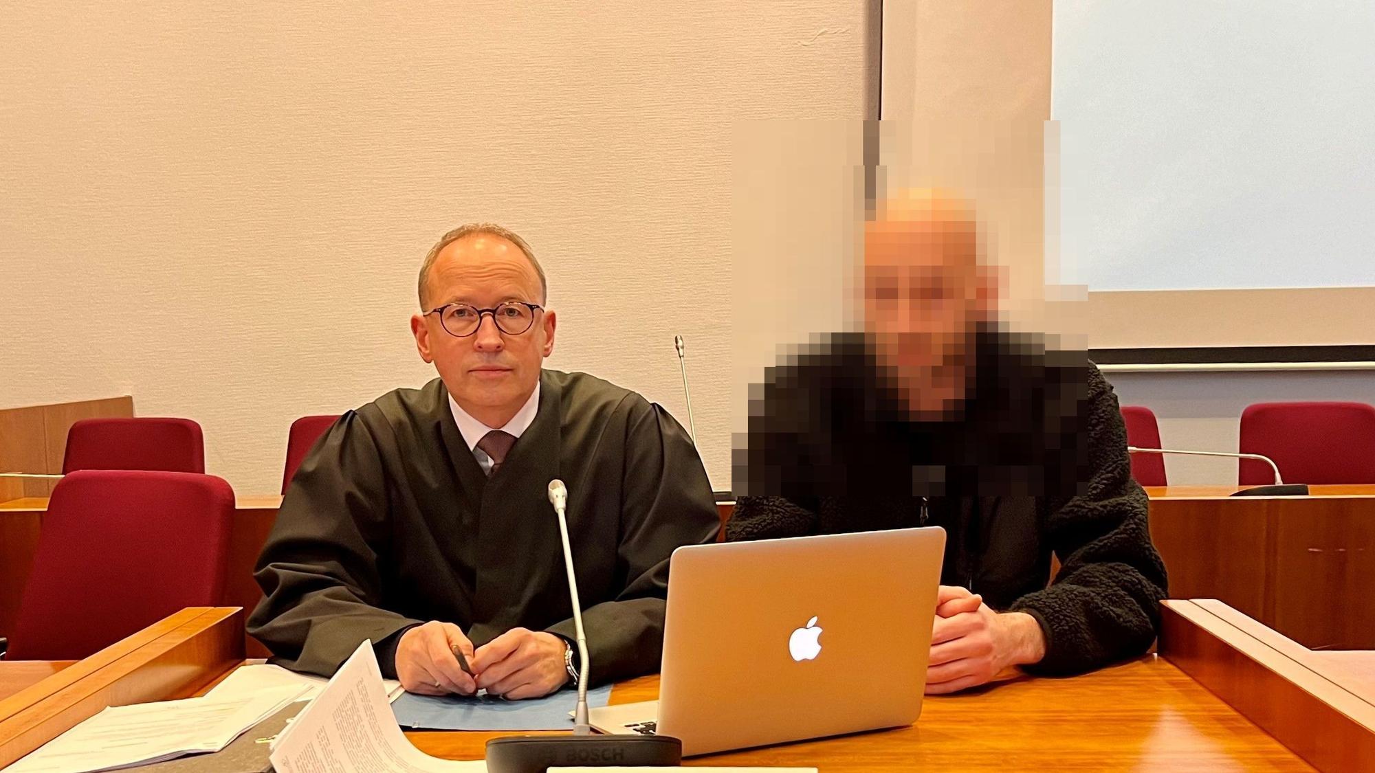 Zwei Männer an einem Tisch, auf dem ein Laptop steht.