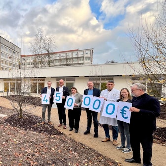 Menschen mit Zahlenschildern auf Klinikumsgelände.