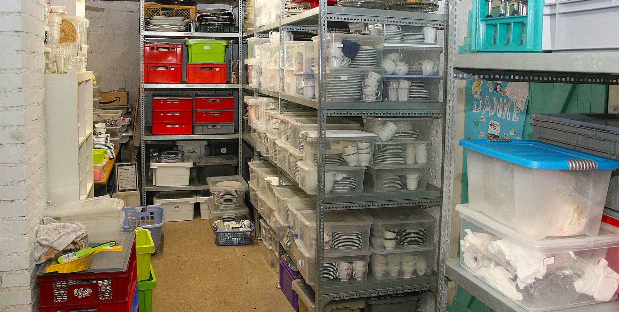 Das Foto zeigt Regale mit Geschirr und andere Utensilien, die in Transportkisten verpackt sind.