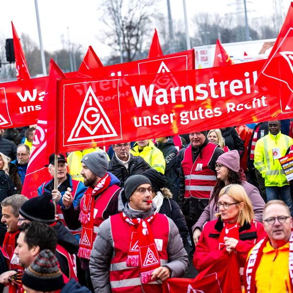 Auf dem Bild sind Streikende zu sehen, die mit roten Schals, Westen und Bannern ausgerüstet sind. (Symbolbild)