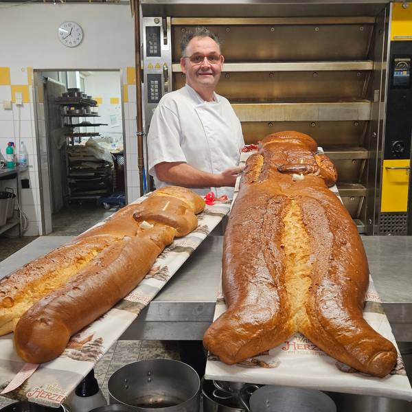 Zu sehen ist ein Bäcker in seiner Backstube mit übergroßen Weckmännern.