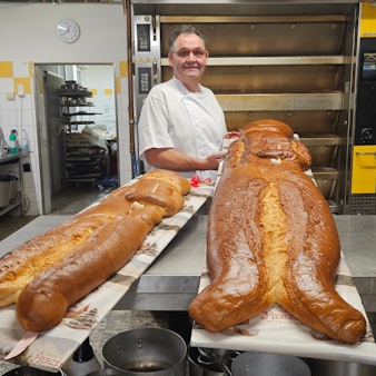 Zu sehen ist ein Bäcker in seiner Backstube mit übergroßen Weckmännern.
