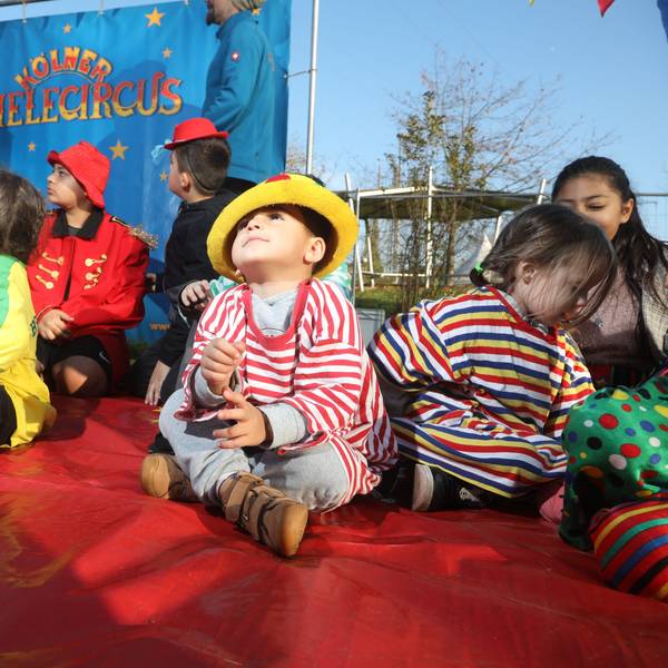 Mehrere Kinder sitzen mit geringelten T-Shirts und bunten Hüten in der Manege des Kölner Spielecircus e.V.