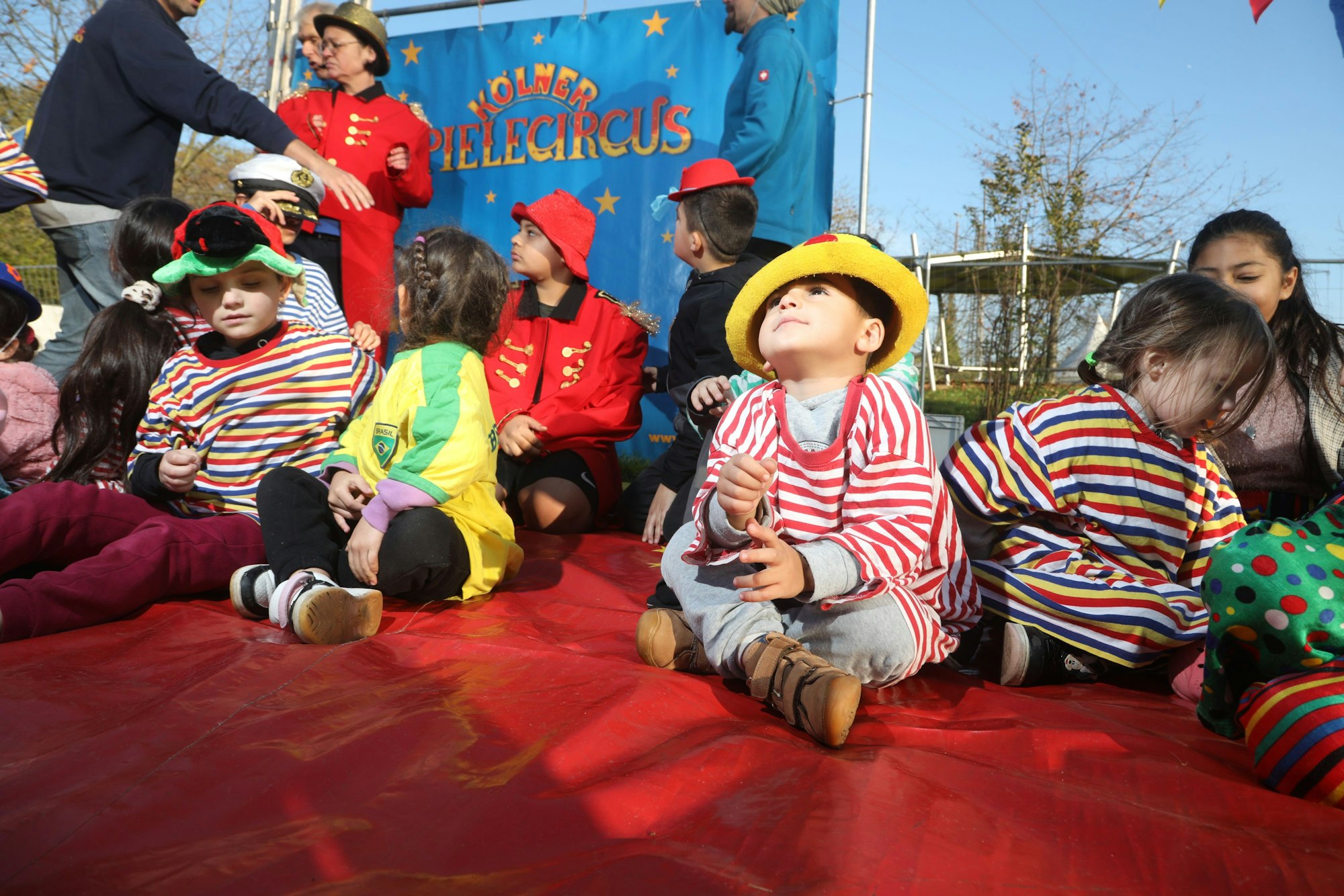Als Artisten verkleidete Kinder aus der Notunterkunft für Geflüchtete in der Vorgebirgsstraße sitzen in der mobilen Manege des Kölner Spielecircus.