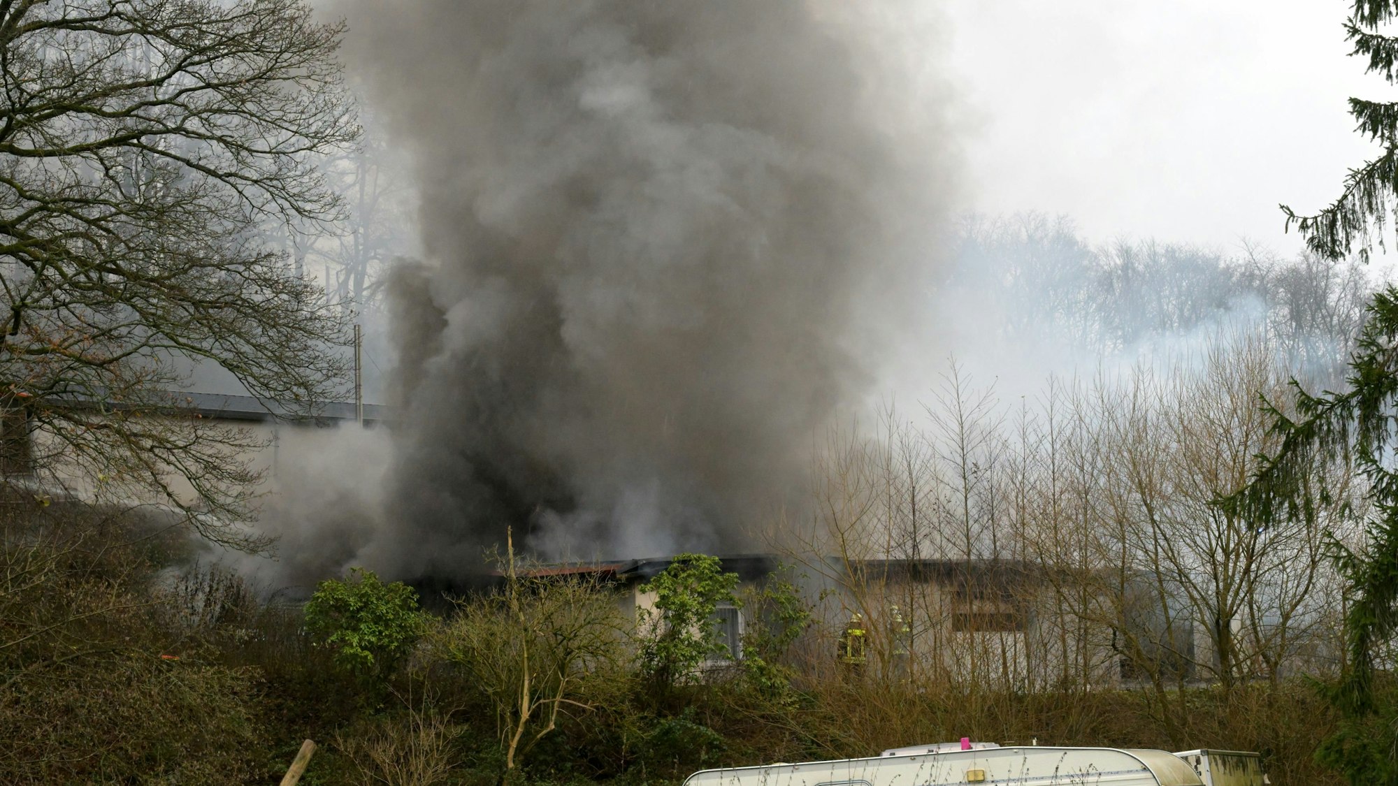 Eine Halle mit Oldtimern Traktoren und Hebebühnen brennt.