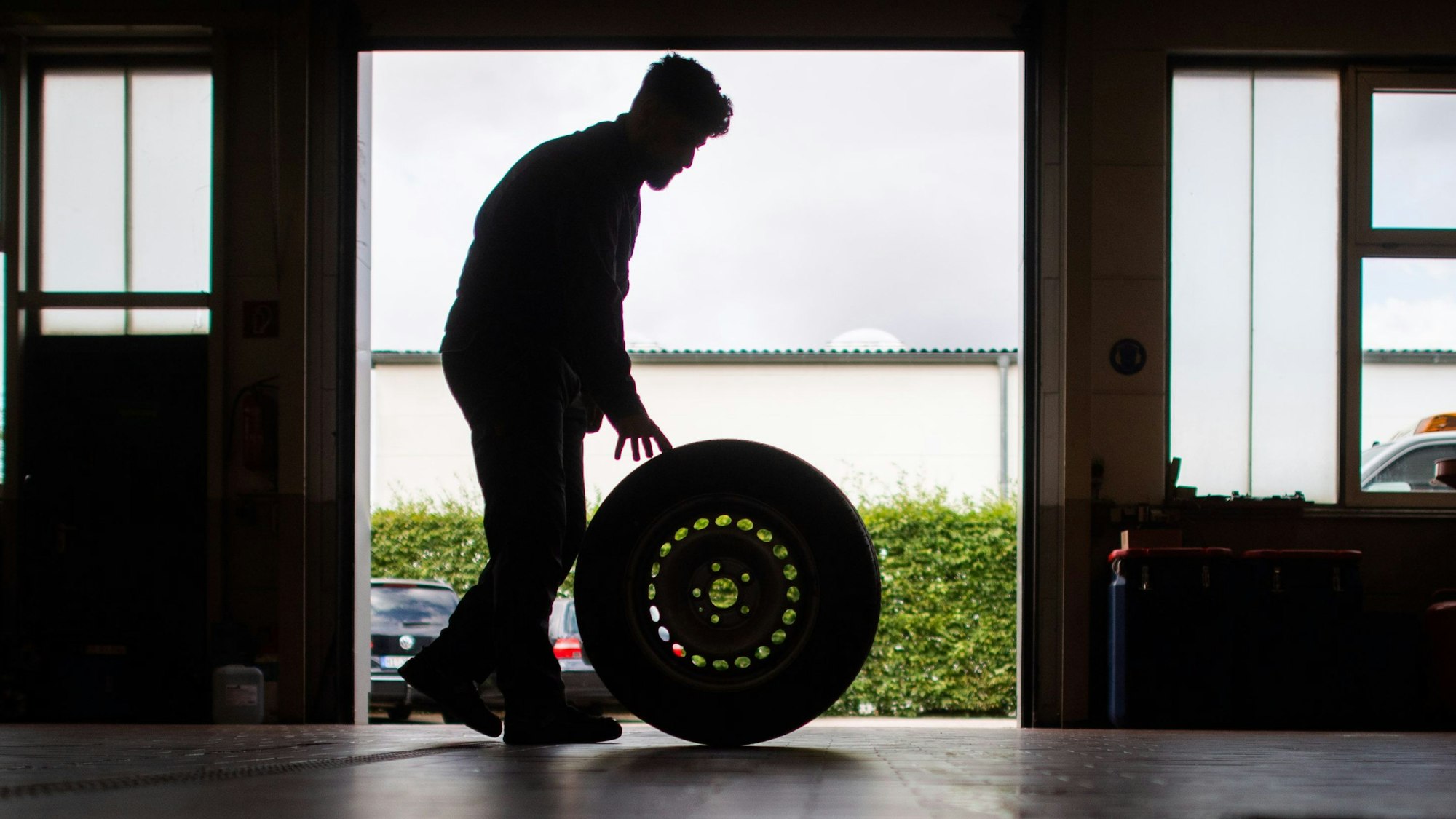 ARCHIV - 22.07.2020, Niedersachsen, Hannover: Ein Auszubildender zum KfZ-Mechatroniker rollt einen Reifen durch eine Werkstatt. (zu dpa: «DGB-Ausbildungsreport: Großteil der Azubis zufrieden») Foto: Julian Stratenschulte/dpa +++ dpa-Bildfunk +++