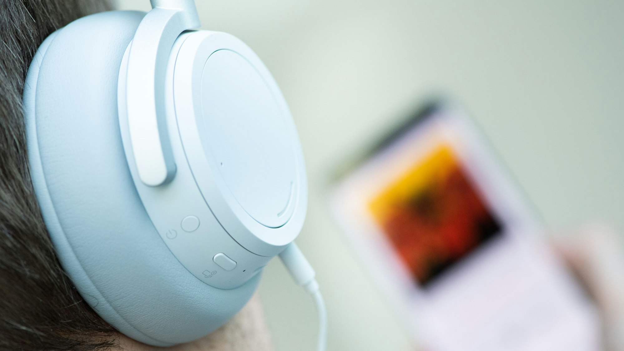 Ein junger Mann hört mit Kopfhörern Musik von seinem Smartphone.